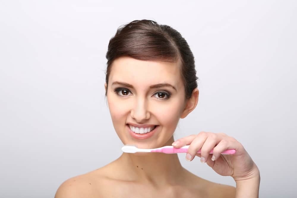 Lady brushing her teeth as part of oral health